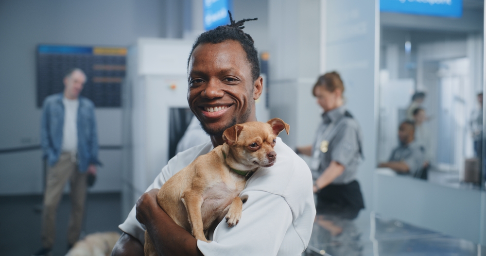 man holding dog at airport terminal during pet travel security showing safe puppy delivery and transport process